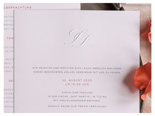 Hochwertige Hochzeitseinladung mit Blindprägung der Initialen und silber geprägten Herzen auf der Einladung und Umschlagsspitze.