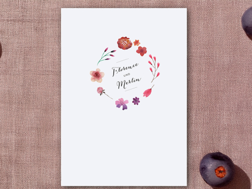 Einladungskarten mit Blumenkranz in Aquarellfarben und lila Briefumschlag.