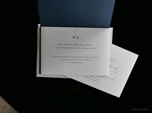 Royale Einladung, gedruckt und in Kupfer geprägt auf Gmund-Papier, umhüllt von einer royalblauen Klappkarte und verpackt in einem edlen Cotton-Briefumschlag.