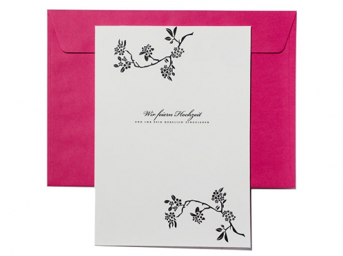 Hochzeitseinladung mit Blütenzweig und pinkem Briefumschlag.