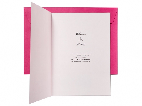 Hochzeitseinladung mit Blütenzweig und pinkem Briefumschlag.