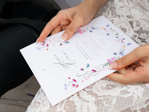 Die Hochzeitseinladung vereint zarte pastellige Blumenranken, minimalistische Typografie und ein silbernes Herz als handgeprägtes Detail – elegant, romantisch und zeitlos.