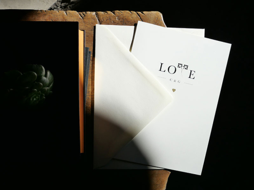 Schlichte Hochzeitseinladung, modern fotografiert mit Goldprägung und Love als Schriftzug. Cremefarbenes Feinpapier mit Briefumschlag.