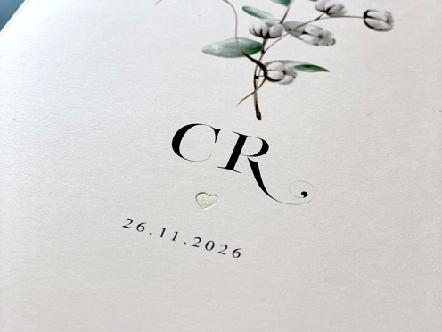 Hochzeitseinladung mit silbernem Herz geprägt, Cotton und Eukalyptus als Aquarellzeichnung im Detail. Initialen und Hochzeitsdatum gedruckt.