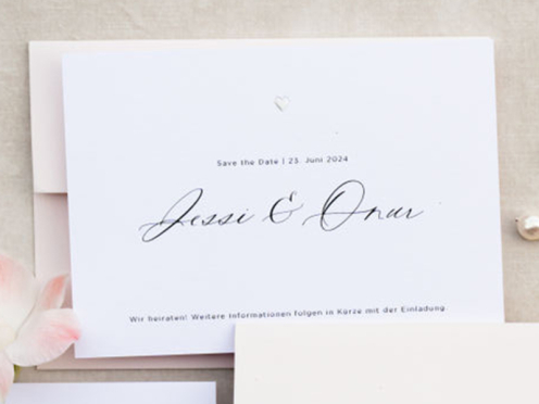 Die Save-the-Date Karte besticht durch feine Typografie und ein erhabenes silbernes Herz. Die Einladung ergänzt das minimalistische Design mit zarten, pastelligen Blumenranken – verspielt, elegant und romantisch.