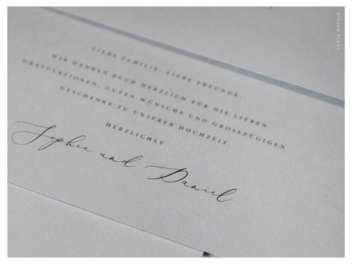 Erleben Sie elegante Einladungen zur Hochzeit mit Ihrem individuellen Monogramm in Goldprägung auf edlem grauem Papier. Der Briefumschlag, verziert mit einem goldenen Herz, ergänzt den exklusiven Look perfekt.