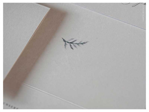 Einladungskarten mit geprägten Initialen auf hochwertigem Papier in edlem Grau. Briefumschlag mit goldenem Herz.